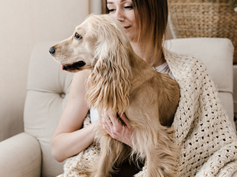 Lady hugging her dog on sofa